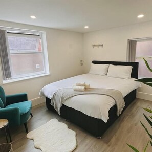 Une chambre à coucher avec un lit, une chaise, une fenêtre et une plante.
