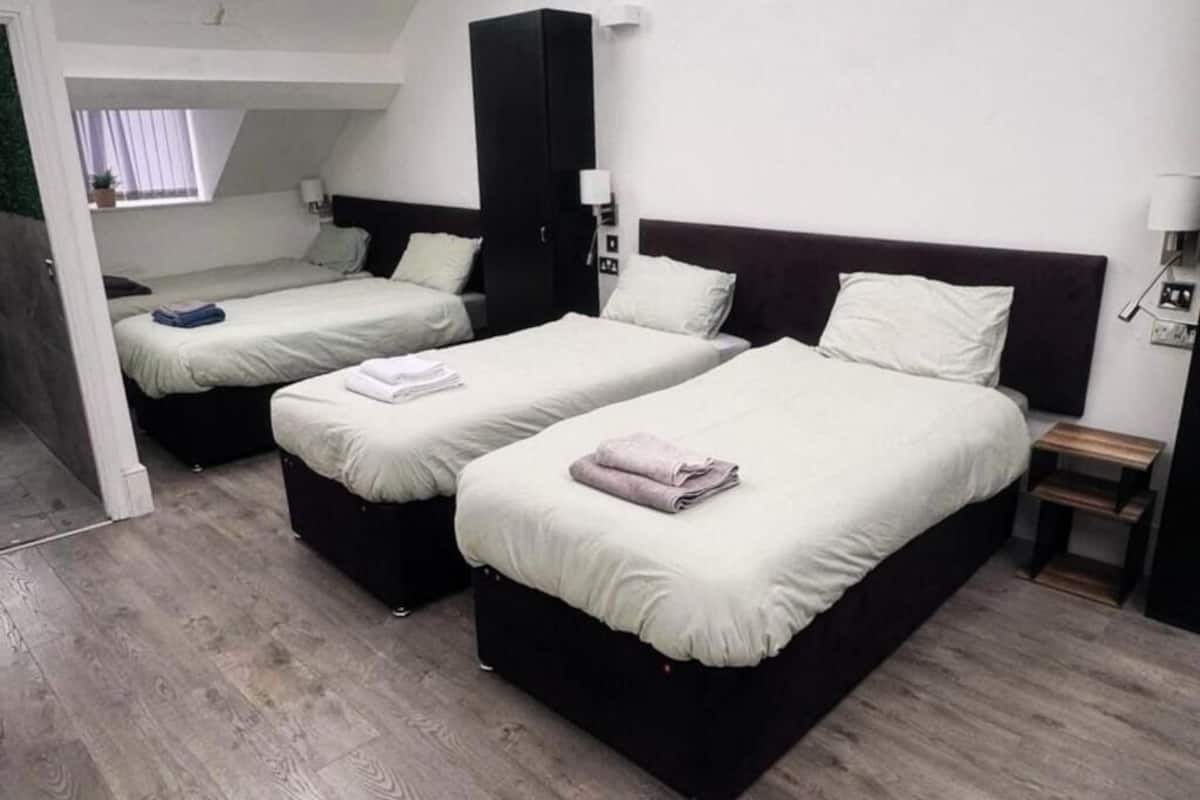 Une chambre d’hôtel avec deux lits, une armoire, une table de chevet et une petite fenêtre.