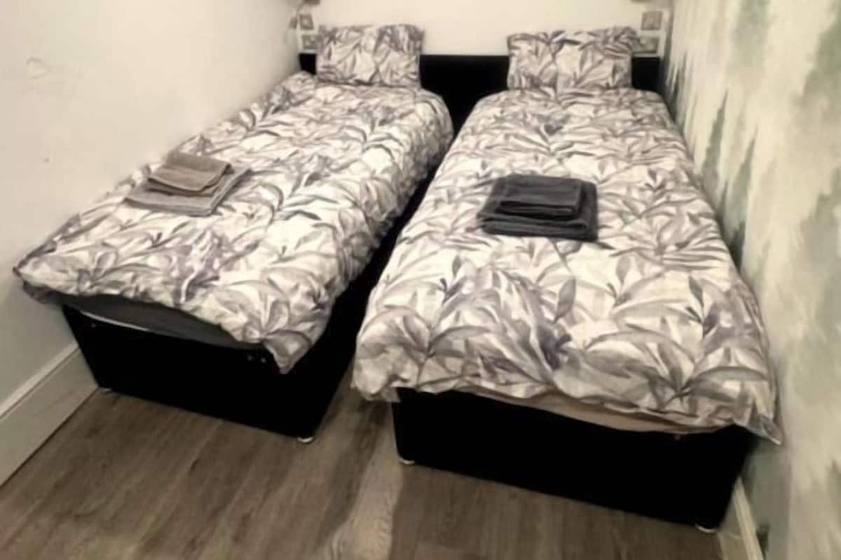 Une chambre avec deux lits, une fenêtre et un petit tapis.