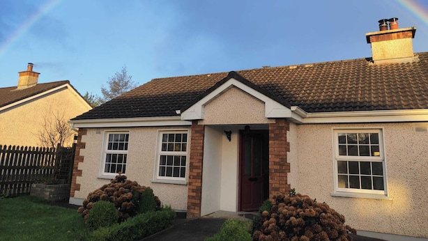 A house with a tiled roof, a brick chimney, and a door.