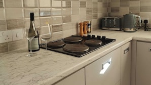 A kitchen with a tiled backsplash, a stove, a toaster, and a bottle of wine.