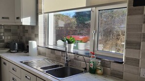 A modern kitchen with a large window, a sink, and a countertop.