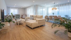 A modern living room with a sectional sofa, a dining area with chairs, a TV, and potted plants. - Bizi Baztan Goienetxea (Elizondo)