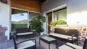 An outdoor patio with wicker furniture, stone walls, and potted plants. - Bizi Baztan Goienetxea (Elizondo)