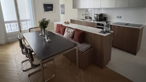 A modern kitchen with a dining area, wooden flooring, and a large window. - Spacious, Quiet and Elegant Apartment in Paris (Paris)