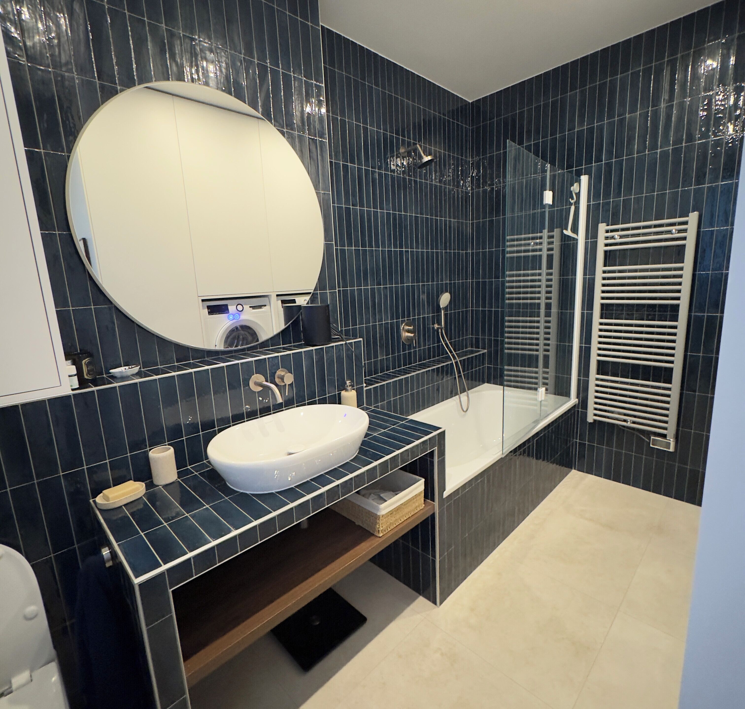 A modern bathroom with a large mirror, a sink, a shower, and a towel rack.