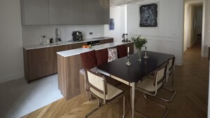 A modern kitchen with a central island, wooden cabinets, and a dining area with a table and chairs. - Spacious, Quiet and Elegant Apartment in Paris (Paris)