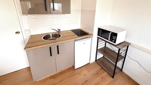 Une cuisine compacte équipée d’un évier, d’un lave-vaisselle, d’un four à micro-ondes et d’un plan de travail en bois.