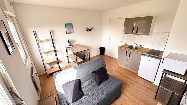 Un espace de vie compact comprenant un coin cuisine, un canapé, une petite table et un radiateur.