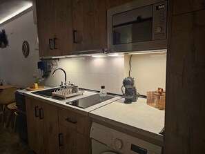 Une cuisine avec des meubles de rangement en bois, un four à micro-ondes, un évier et un lave-vaisselle.