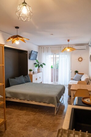 A bedroom with a bed, a desk, a chair, a TV, and a plant. - Apartment Near the Beach in El Bajoncillo (Torremolinos)