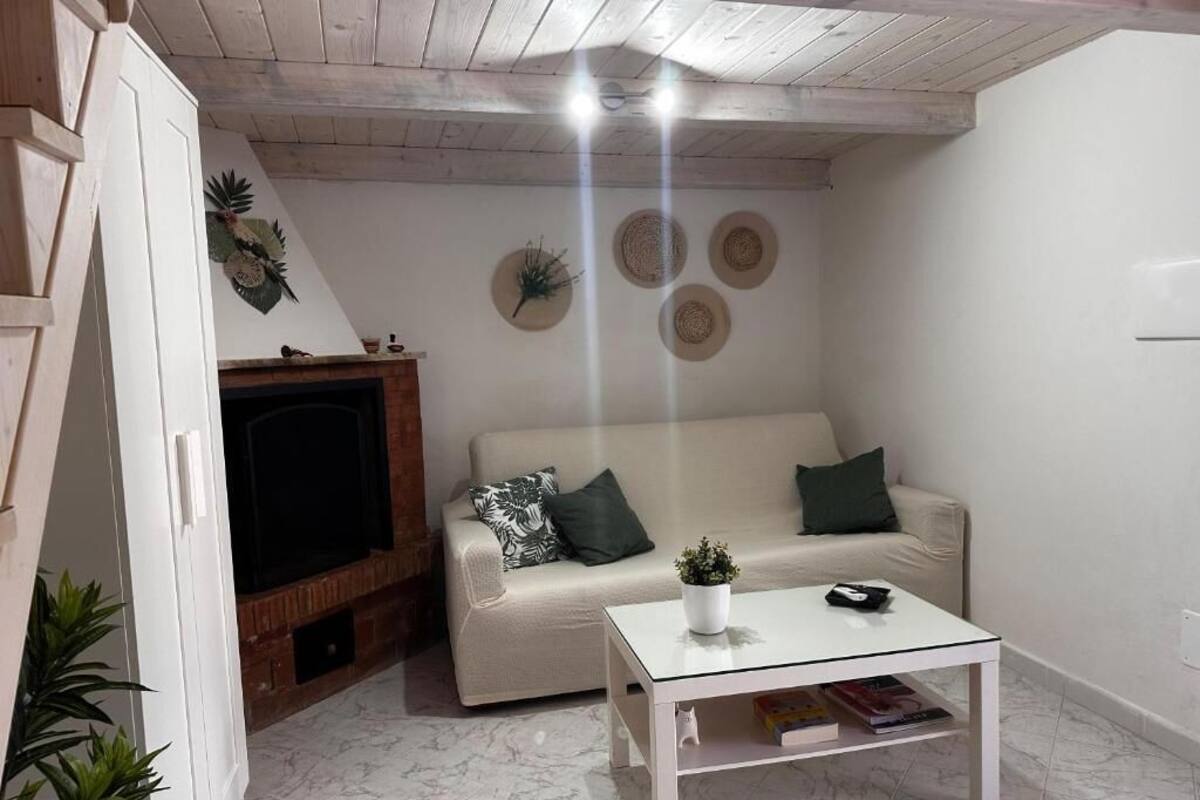 A living room with a sofa, a coffee table, a fireplace, and a ceiling with exposed beams.