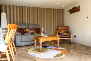 Ein Wohnzimmer mit einer Couch, zwei Sesseln, einem Holztisch und einem gemusterten Teppich.
