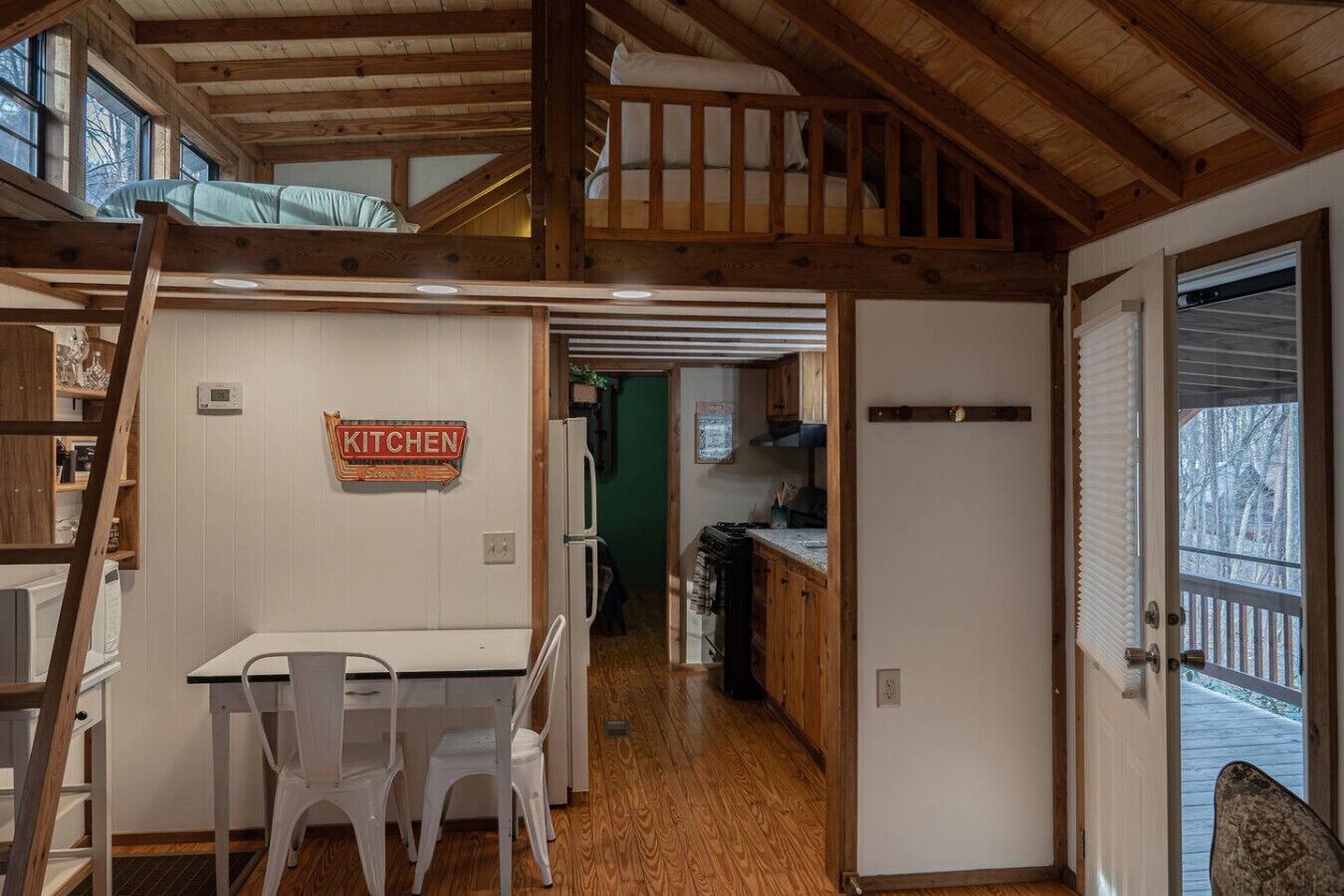 Une chambre de style loft avec un lit superposé, un coin cuisine et un espace repas comprenant une table et des chaises.