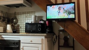 Eine Küche mit Mikrowelle, Kaffeemaschine und Fernseher an einer Holztreppe.