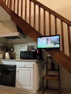 A kitchen with a microwave, coffee maker, and a television mounted on a wooden staircase. - A must-see: directly on the beach with parking! (Sainte-Marie-la-Mer)
