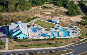 Luftaufnahme eines Resorts mit großem Poolbereich, mehreren Wasserrutschen und einem Parkplatz.