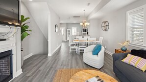 Een moderne woonkamer met een open haard, een eethoek en een trap naar een verdieping erboven.