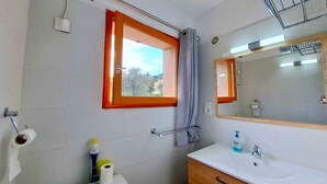 Een badkamer met raam, spiegel, wastafel en toilet.