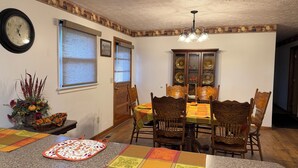A dining area with a table set for four, a chandelier, and a decorative wall clock.