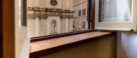 Una ventana con vista a un edificio que presenta un reloj y una estatua.