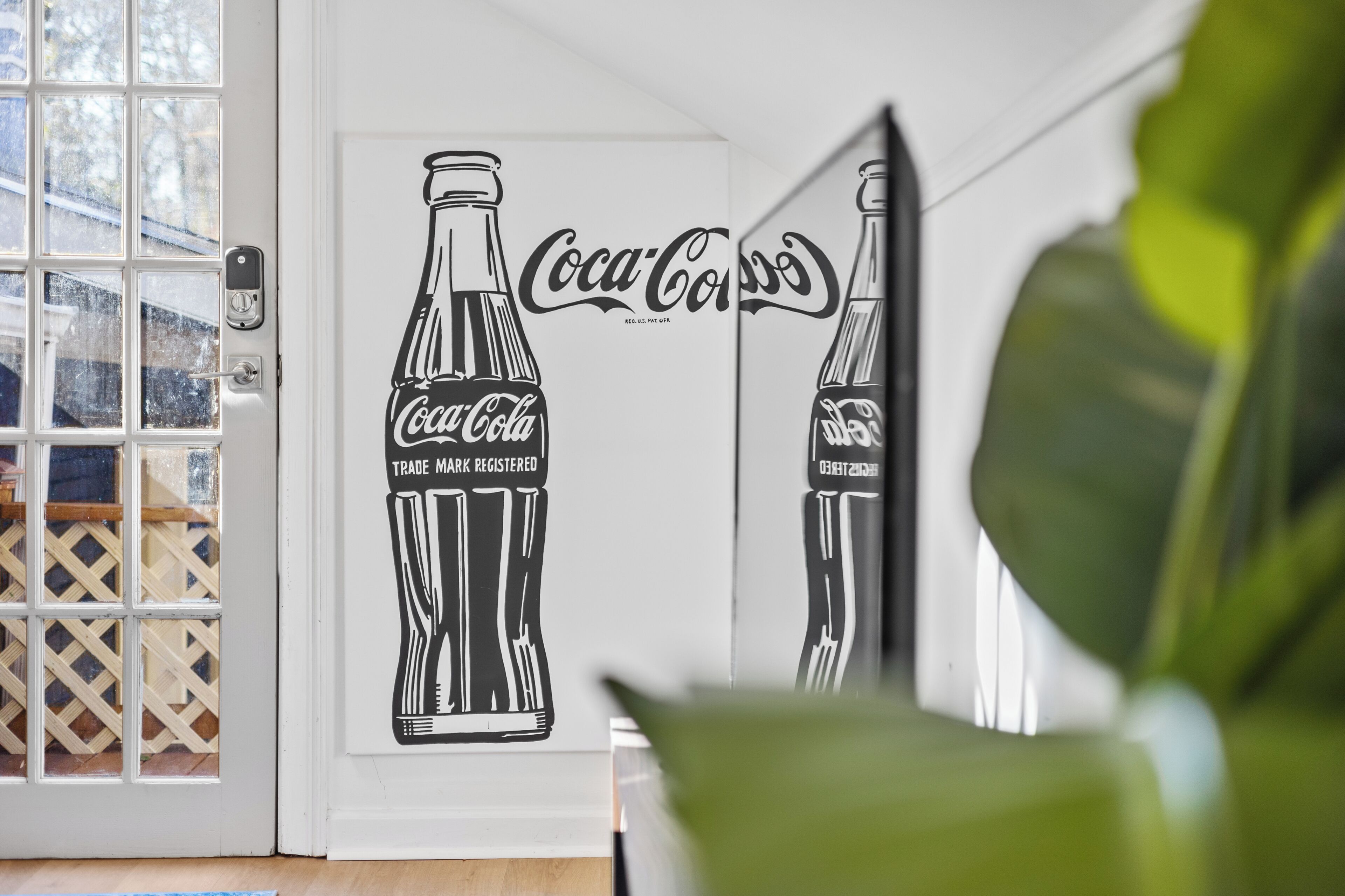 A door with a Coca-Cola logo and a mirrored image of a bottle.