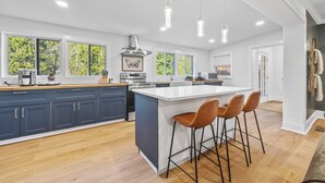 Una cocina moderna con una isla grande, taburetes de bar e iluminación colgante.