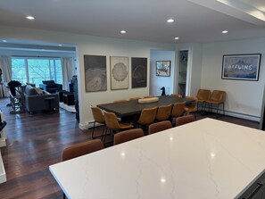 A modern dining area with a large table, brown chairs, and a white marble countertop. - Beautiful 4BR Lake House - New 2026 - Boat Slip - Located on Large Compound (Laconia)