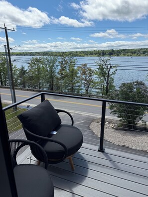 A balcony with a view of a lake, a chair, and a table. - Beautiful 4BR Lake House - New 2026 - Boat Slip - Located on Large Compound (Laconia)