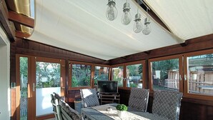 A sunroom with a table, chairs, a TV, and a view of the outdoors.