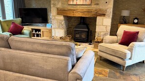 A living room with a stone fireplace, sofas, a television, and a painting. - Luxury Cotswold Cottage Can Sleep 8. Secure Garden & Parking.  Walks From Door (Poulton)