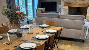 A dining area with a table set for four, a sofa, and a fireplace. - Luxury Cotswold Cottage Can Sleep 8. Secure Garden & Parking.  Walks From Door (Poulton)