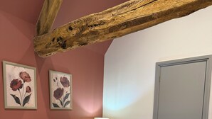 A hotel room with two beds, a wooden ceiling beam, a door, and two framed floral paintings on the wall. - Luxury Cotswold Cottage Can Sleep 8. Secure Garden & Parking.  Walks From Door (Poulton)