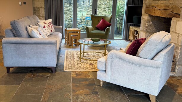 A living room with two grey sofas, a green armchair, a wooden coffee table, and a stone fireplace. - Luxury Cotswold Cottage Can Sleep 8. Secure Garden & Parking.  Walks From Door (Poulton)