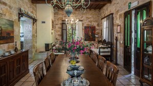 A dining room with a wooden table, chairs, a chandelier, and a vase with flowers. - Kissamos Luxury Villa for 4 Guests (Kissamos)