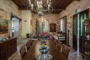 A dining room with a wooden table, chairs, a chandelier, and a vase with flowers. - Kissamos Luxury Villa for 4 Guests (Kissamos)