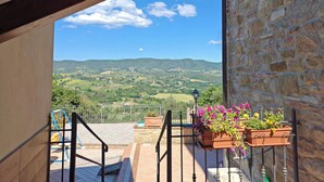 Un balcone con vista su dolci colline verdi e un cielo sereno.
