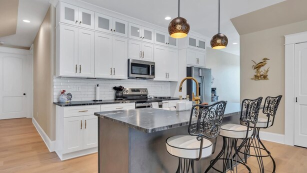 A modern kitchen with white cabinets, stainless steel appliances, and a central island with bar stools.