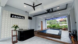 A modern hotel lobby with a reception desk, a large indoor water feature, and a view of the outdoor garden.
