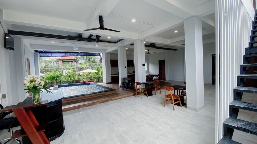 A spacious indoor area with a pool, dining area, and a staircase.