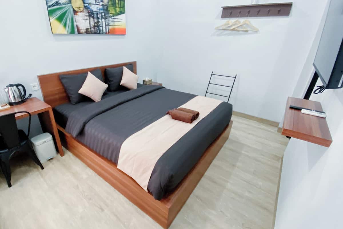 A bedroom with a bed, desk, chair, and a TV.