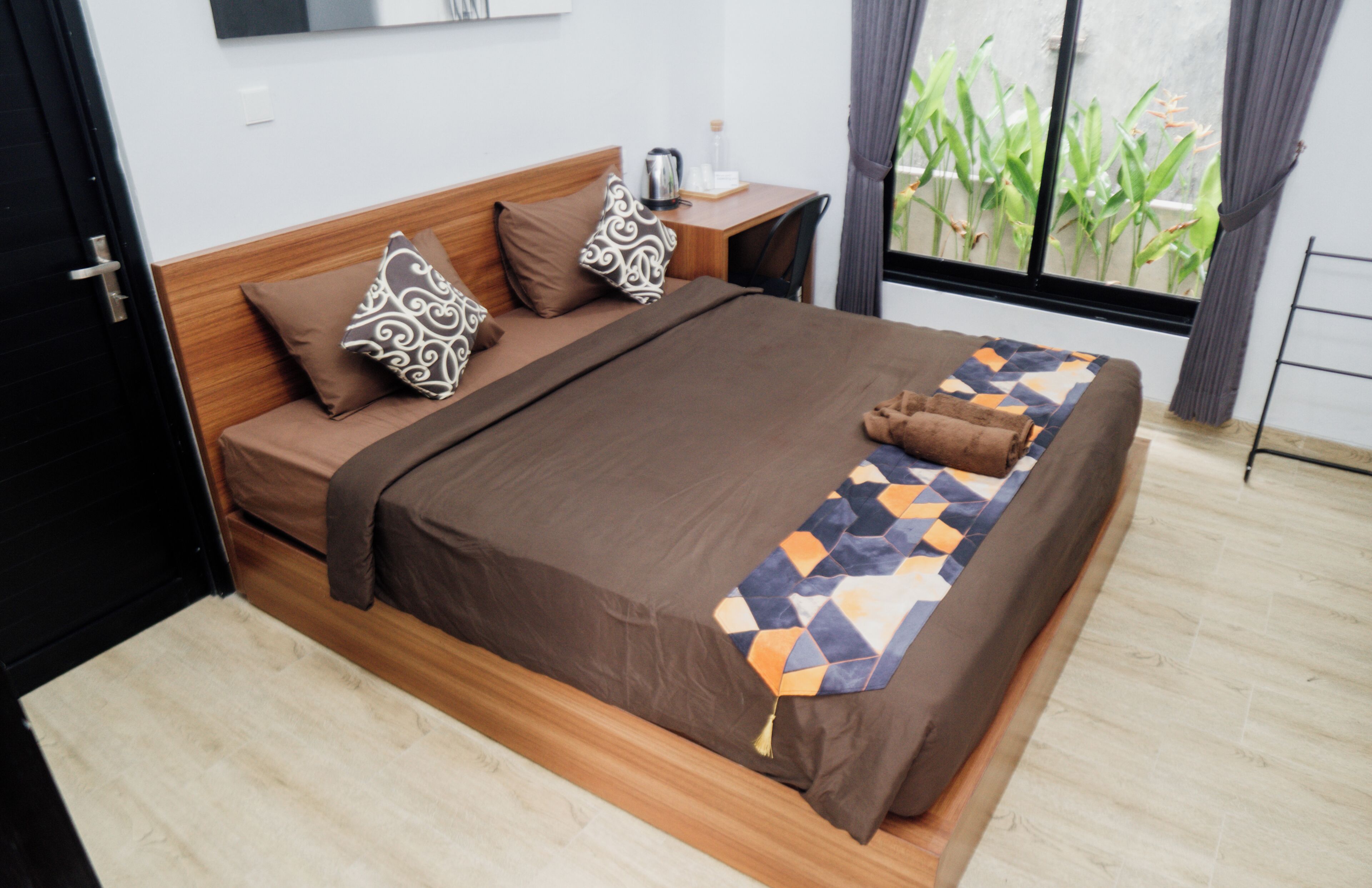 A neatly made bed with a geometric-patterned blanket, a wooden headboard, and two patterned pillows.