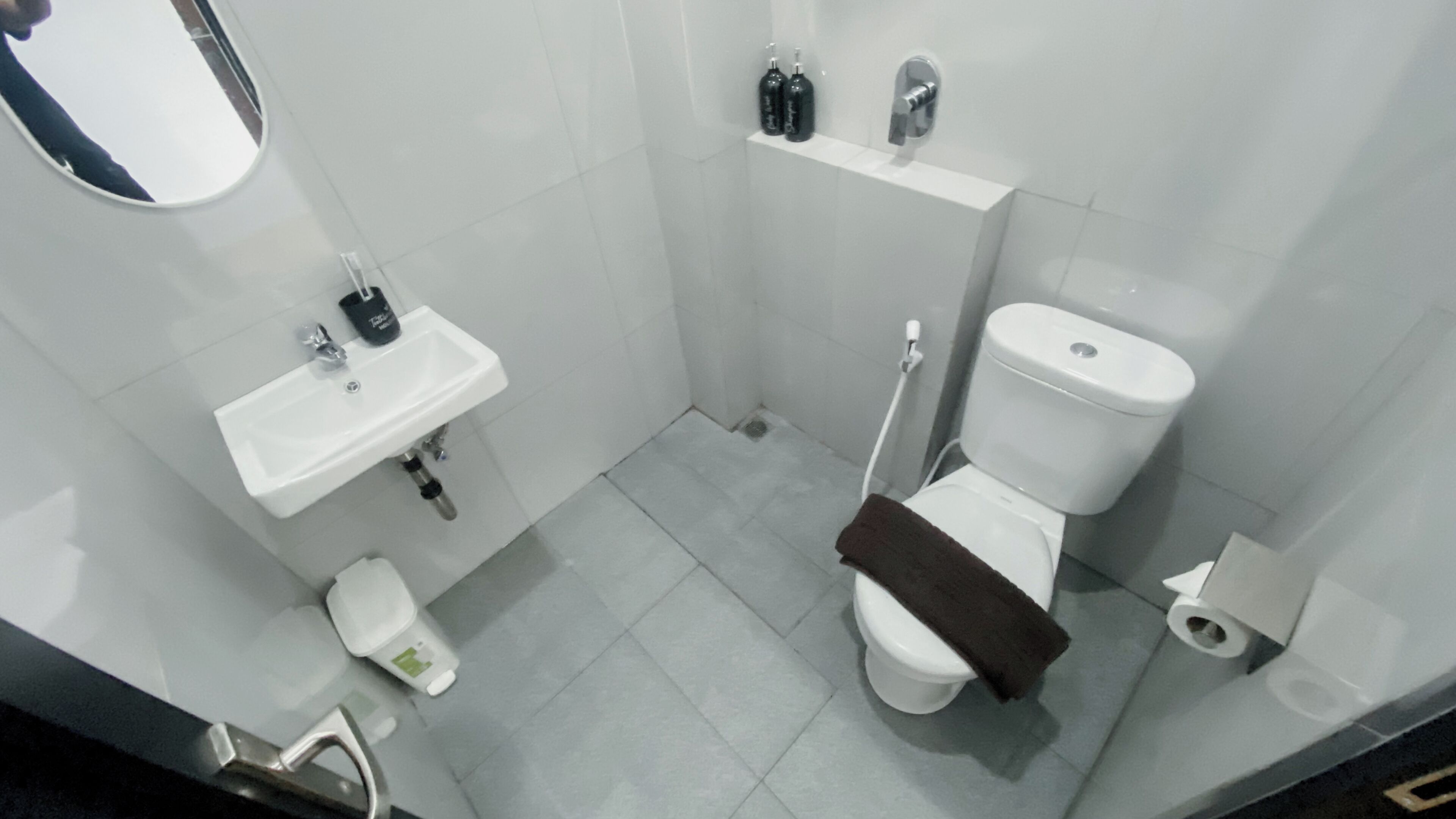 A small, modern bathroom with a white sink, toilet, and shower.