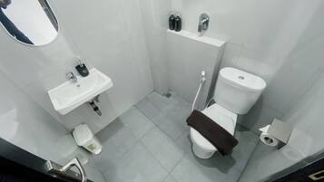 A small, modern bathroom with a white sink, toilet, and shower.