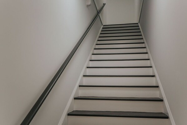 A staircase with a handrail, white walls, and a landing area.