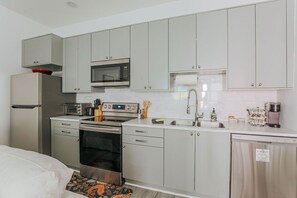 A compact kitchen with a microwave, oven, sink, and a coffee maker.