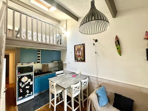 Eine kompakte Küche mit Essbereich, ein Schlafschlaff mit Balkon und einer Wandleuchte.