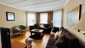 Un salon avec un canapé, un fauteuil, une table basse et un chien.