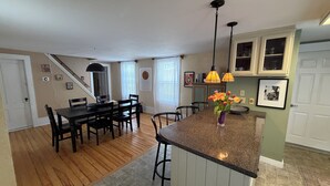 Une cuisine dotée d’un îlot central, d’un coin repas avec des chaises et d’un escalier menant à un autre niveau.
