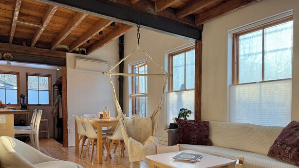 Un salon chaleureux avec un plafond en bois, un coin repas et de grandes fenêtres.
